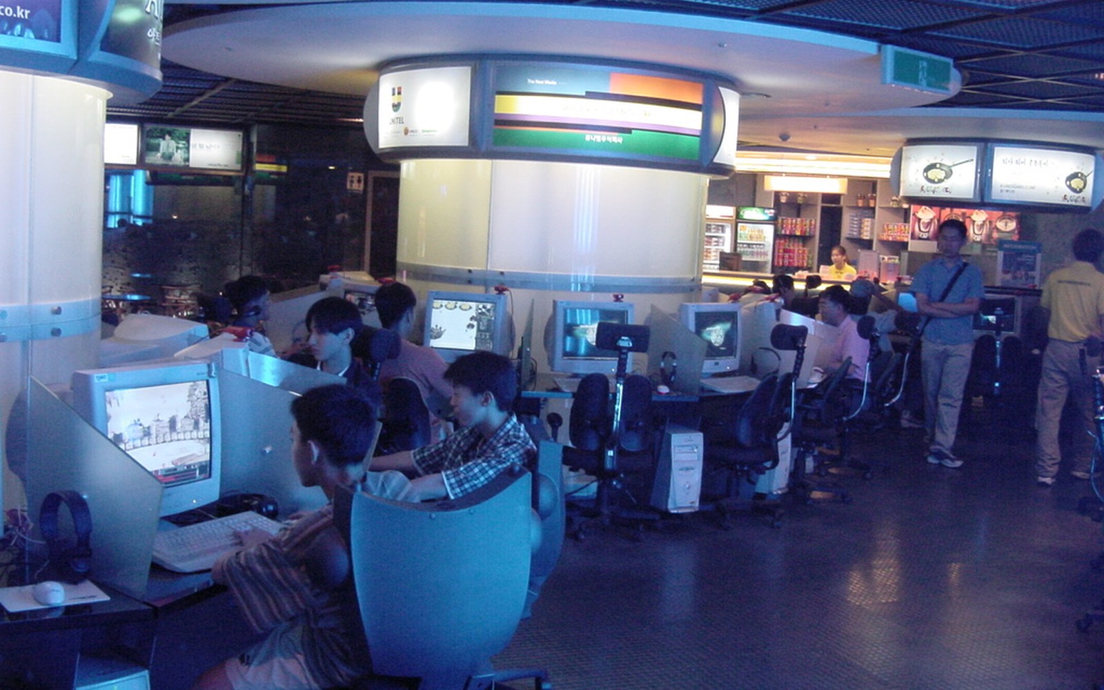Rows of computer terminals at a Korean PC bang with customers seated at monitors